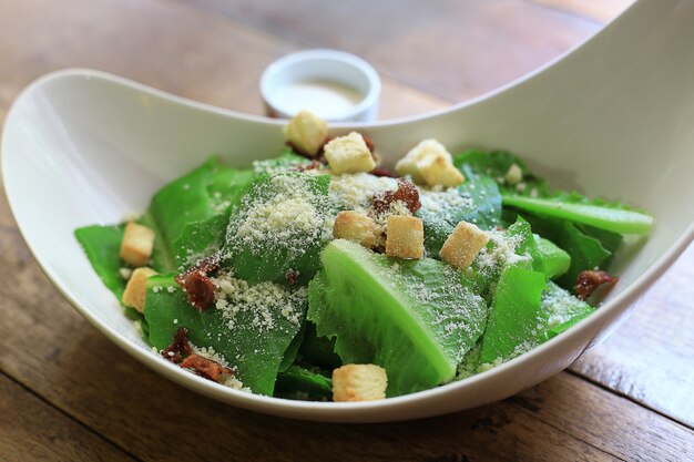 Caesar Salad gesunde Mittagsschüssel. mit Soße in Tassen auf Holztisch Hintergrund.