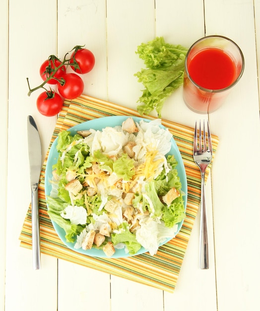 Caesar-Salat auf blauem Teller auf farbigem Holzhintergrund