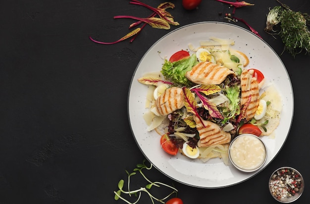 Caesar-Salat auf schwarzem Hintergrund mit Kopienraum für Text oder Rezept, Ansicht von oben