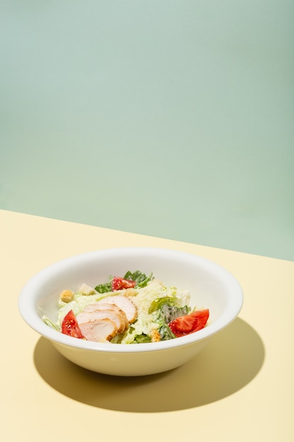 Caesar-Salat in weißer Platte auf gelbem hartem Schatten modernes hochwertiges Foto
