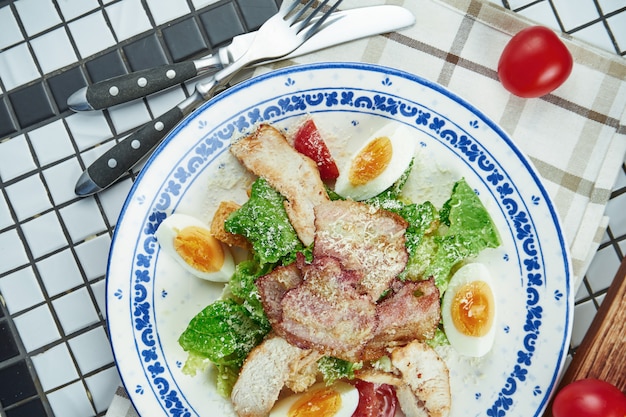 Caesar Salat mit Croutons, Parmesan, Huhn, Ei in einer weißen stilvollen Schüssel. Restaurant servieren. Selektiver Fokus, Holztisch