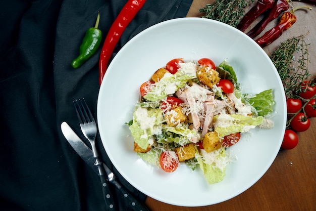 Caesar Salat mit Croutons, Parmesan, Huhn, Ei in weißem Teller auf Holztisch. Restaurant servieren. Nahansicht