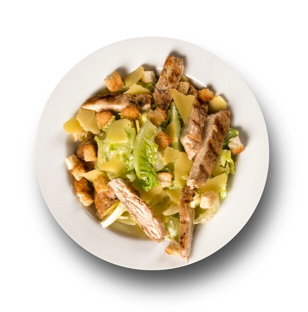 Caesar Salat mit Croutons und gegrilltem Hähnchen auf weißer Oberfläche.