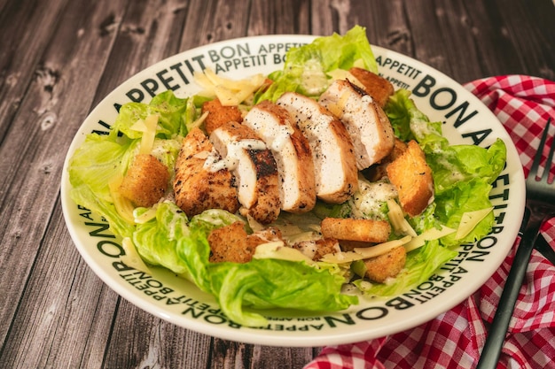 Caesar-Salat mit dünn geschnittener Hähnchenbrust und traditionellem Aioli auf einem Teller, der guten Appetit sagt