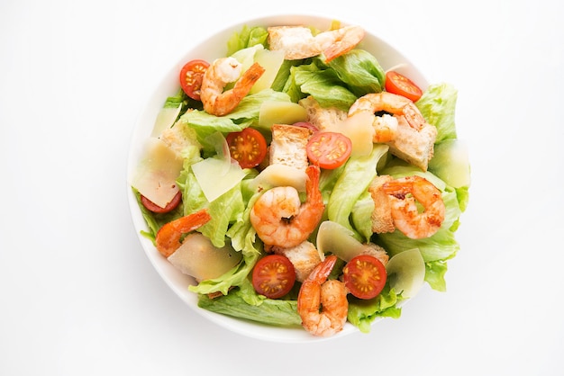 Foto caesar-salat mit frischen blättern, garnelen, kirschtomaten in einem teller isoliert auf weißem hintergrund. nahansicht