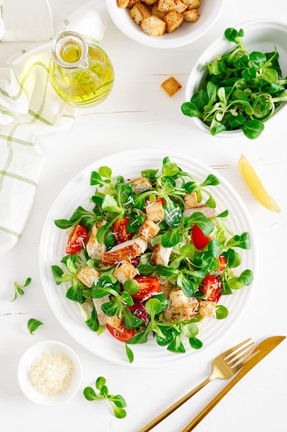 Caesar-Salat mit gegrilltem Hühnerfleisch, frischen Tomatencroutons, Feldsalat und Parmesankäse, gesundes Mittagessen, Ansicht von oben