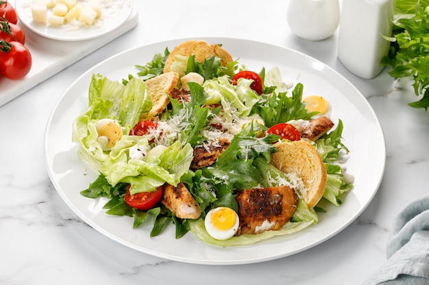 Caesar-Salat mit gerösteten Hühnerfleisch-Tomaten-Croutons und Parmesan-Käse in weißer Platte