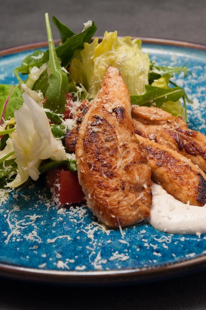 Caesar-Salat mit Hähnchenfilet auf einer blauen Platte Nahaufnahme