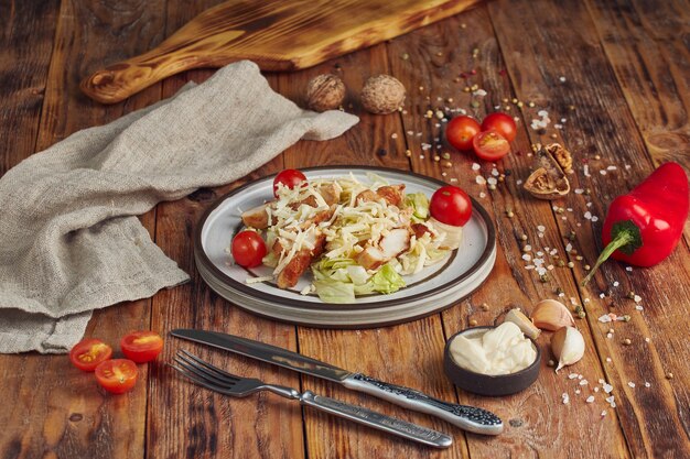 Caesar Salat mit Huhn in einem weißen Teller auf Holztisch