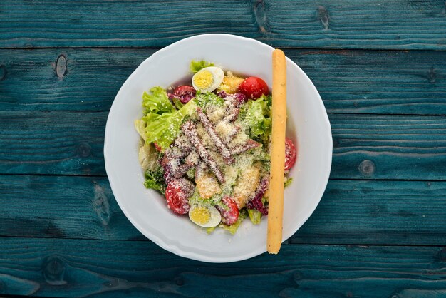 Caesar-Salat mit Rindfleisch. Auf einem blauen hölzernen Hintergrund. Ansicht von oben. Kopieren Sie Platz für Ihren Text.