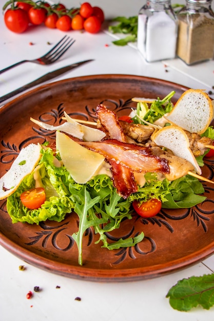Caesar-Salat und Hühnerspieße auf einem braunen Teller auf vertikaler Ausrichtung mit weißem Hintergrund