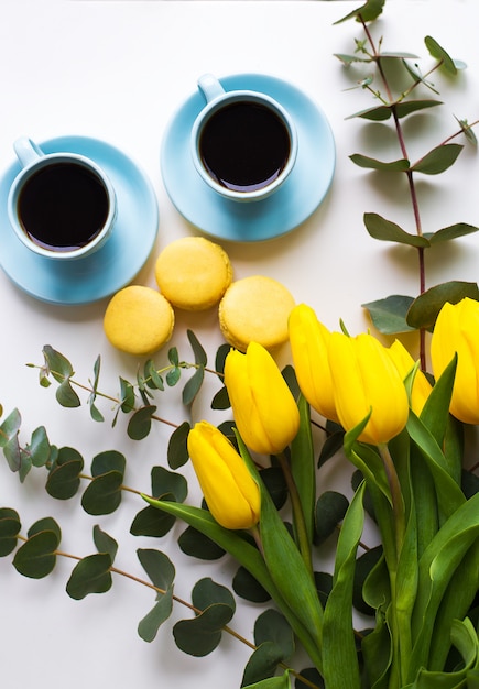 Café acabado de fazer, macarons e buquê de tulipas amarelas