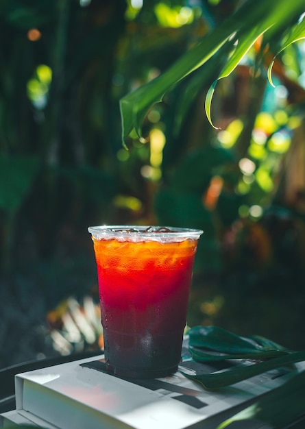 Café americano helado o café negro en vaso de plástico sobre una mesa de madera en el jardín