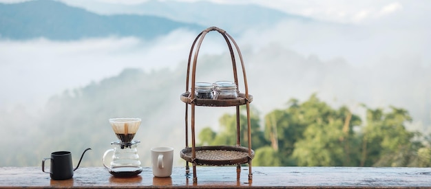 Café arábica por equipamento de gotejamento de café Vintage colocado em mesa de madeira pela manhã com fundo de montanha e natureza