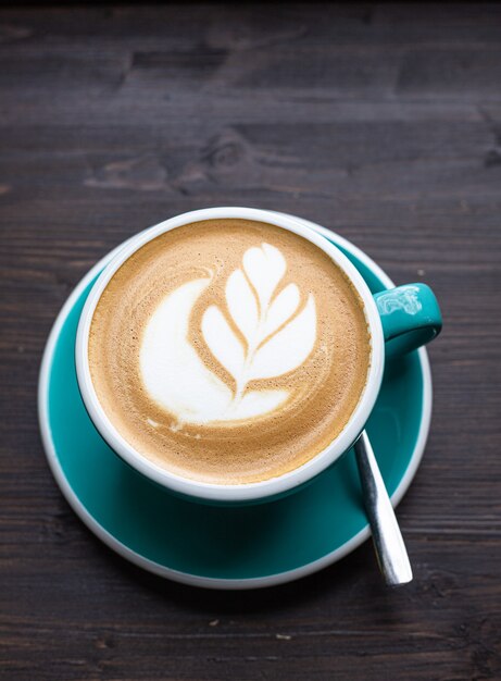 Café con arte latte en taza de cerámica en la mesa de madera en la cafetería o cafetería Vista superior