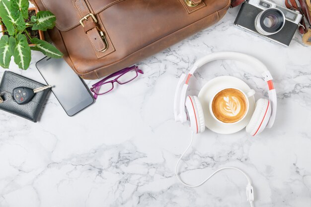 Café con auriculares y bolso de cuero vintage, smartphone y cámara vintage