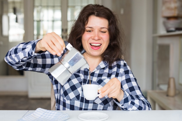 Café, bebidas e conceito de refeição - jovem mulher com cafeteira derramando café na xícara.