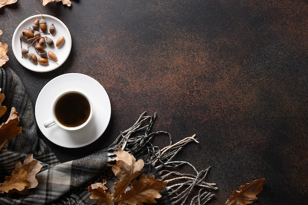 Café de bellota y bufanda acogedora, hojas de roble de otoño sobre mesa marrón. Vista desde arriba. Copie el espacio. Sustituto del café sin cafeína.