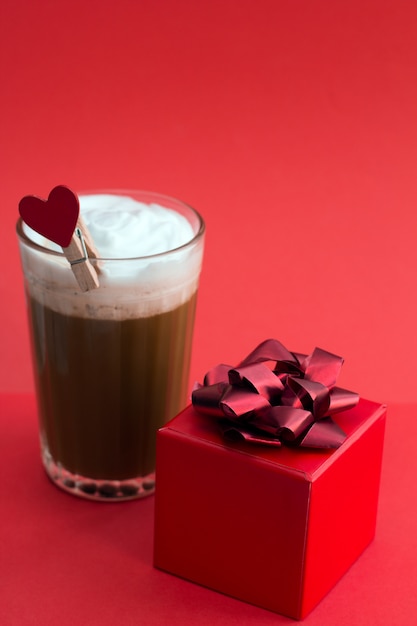 Café y caja de regalo roja sobre rojo.