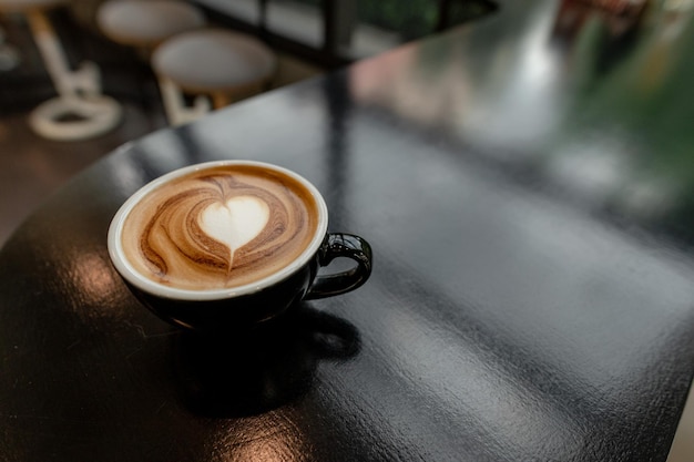 café caliente con forma de corazón de arte latte en mesa negra