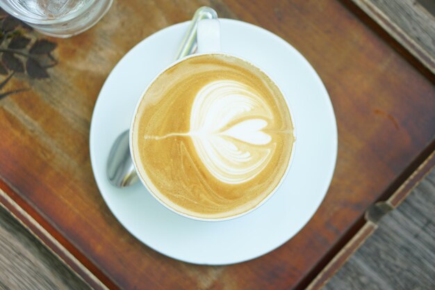 Café caliente en forma de flor colocado sobre una mesa de madera