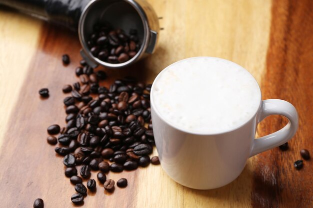 Café caliente con leche y espuma de leche en el suelo de madera