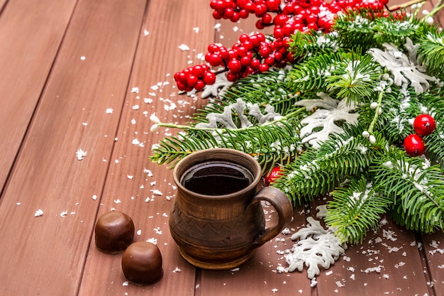 Café caliente de navidad. Abeto de año nuevo, rosa de perro, hojas frescas, dulces de chocolate y nieve artificial.