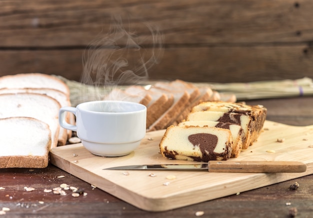 Café caliente con pastel y pan en la mesa de madera