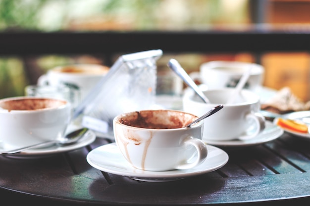 El café caliente en una taza se bebe en la mesa con enfoque suave y luz en el fondo