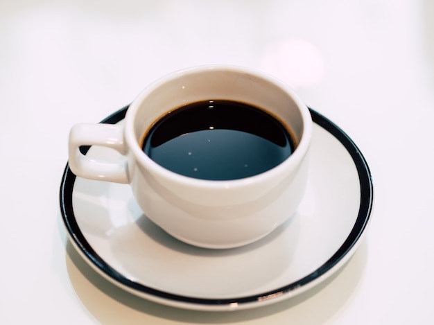 Café caliente en taza blanca servida sobre la mesa en una tienda muy tranquila.