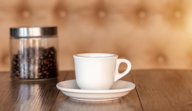 Café caliente en una taza blanca sobre una mesa de madera oscura en un café