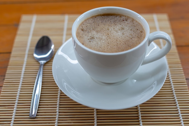 Café caliente en una taza blanca sobre la mesa.