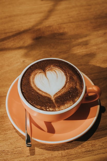 Café caliente en taza en el foco suave de la tabla de madera, efecto retro entonado.