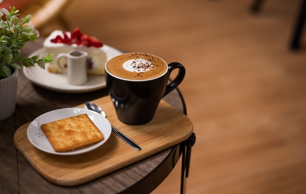 Café caliente en una taza en la mesa de madera