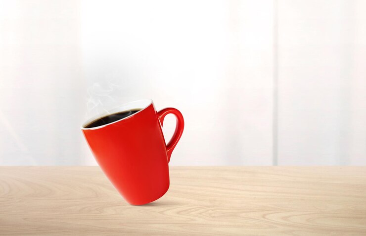 Café caliente en taza roja en una mesa de madera Hay un espejo blanco en el fondo