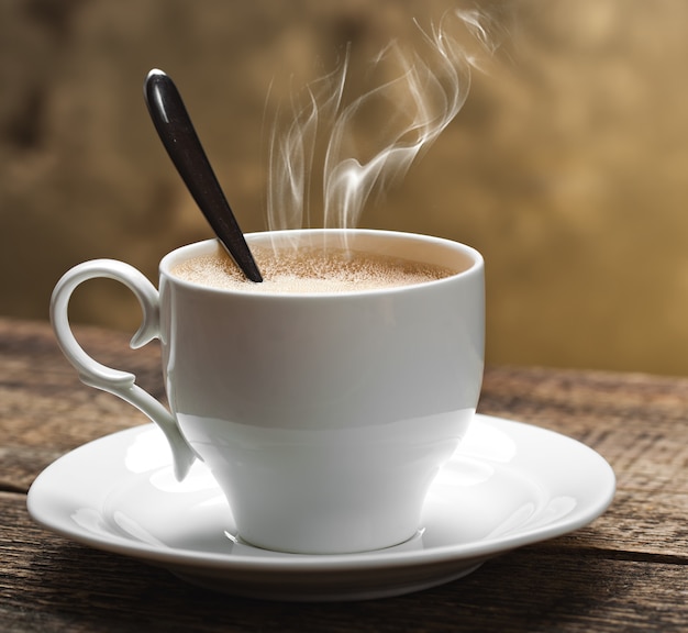 Foto café caliente en una taza sobre un fondo antiguo