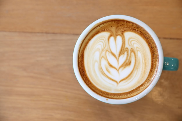 Café capuchino caliente en cafetería en mesa de madera