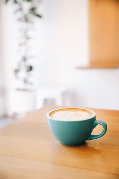 Café capuchino caliente en cafetería en mesa de madera