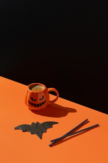 Café capuchino con leche en taza de calabaza sobre fondo naranja negro concepto de celebración de halloween
