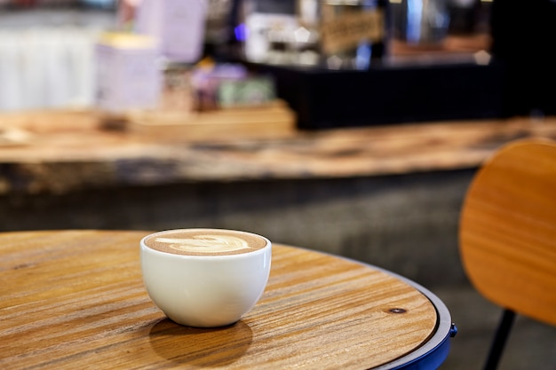 Café capuchino en mesa de madera en cafetería