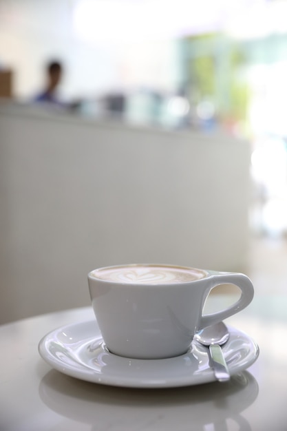 Café Ccappuccino o Latte art hecho con leche en la mesa blanca en la cafetería.