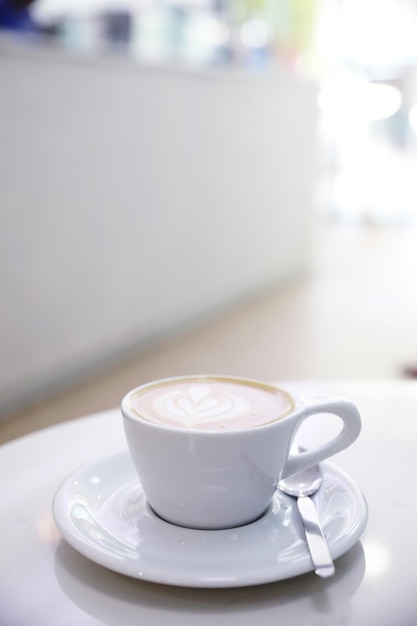 Café ccappuccino o Latte art hecho con leche en la mesa blanca de la cafetería