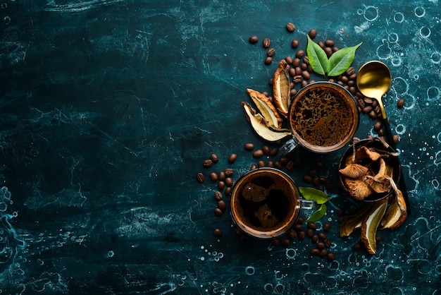 Café de champiñones en una taza y granos de café bebida de moda sobre un fondo de piedra negra Vista superior Espacio libre para texto