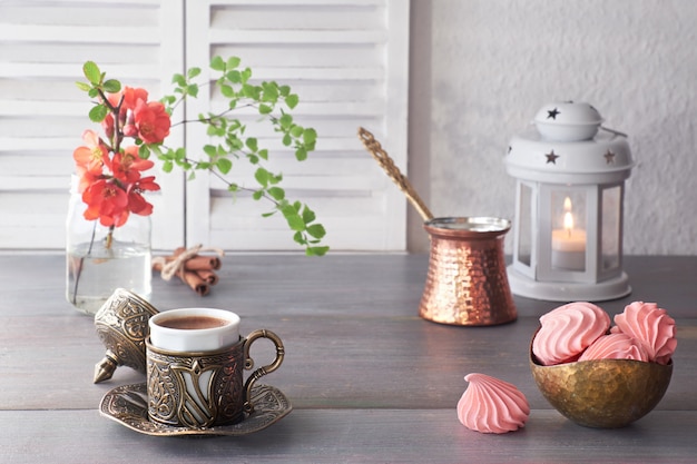 Café cocinado en una olla tradicional de cobre turco y servido en una taza de metal y cerámica