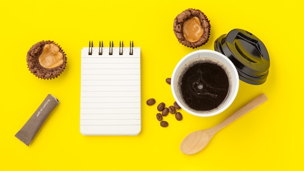 Café com brownie e notebook em fundo amarelo