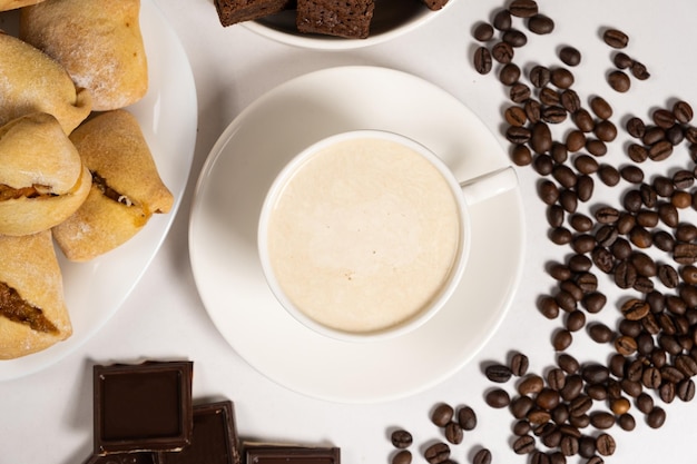 Café com creme de leite em uma xícara de cerâmica branca e bolo de chocolate sobre a mesa Delicioso cappuccino aromático café da manhã