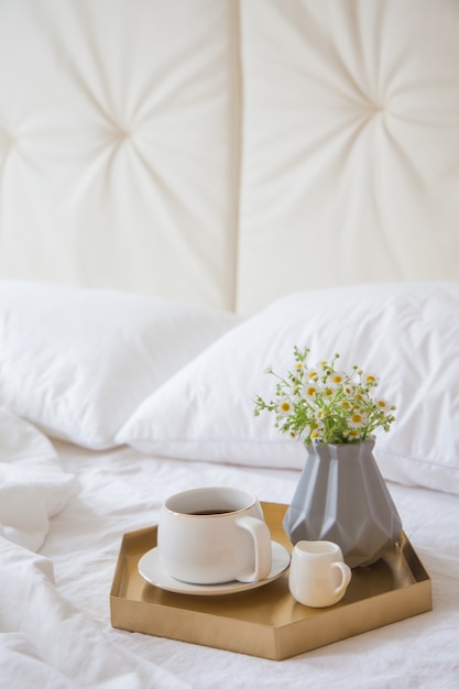 Café com flores em uma bandeja na cama