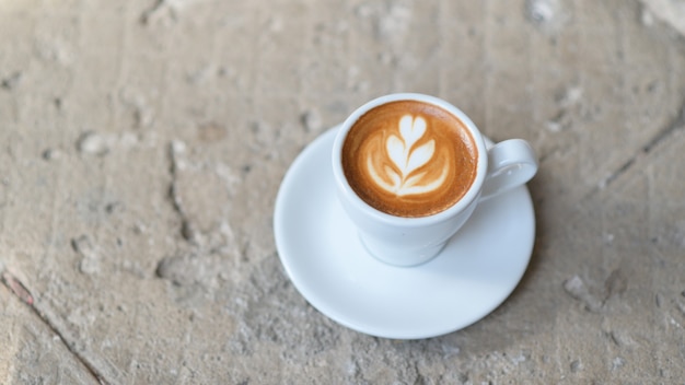 Café com leite coração textura na mesa de concreto.