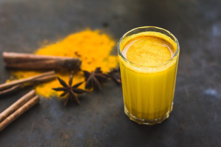 Café com leite de cúrcuma de desintoxicação saudável. Leite dourado com cúrcuma, especiarias e limão em um fundo escuro. Bebida ayurvédica saudável. Fortalecimento do sistema imunológico. Antioxidante e superalimento