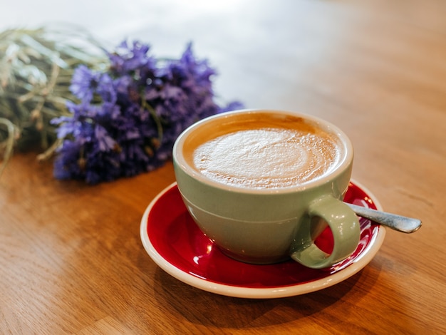 Café com leite em mesa de madeira com flor centáurea em efeito de filtro de filme retrô
